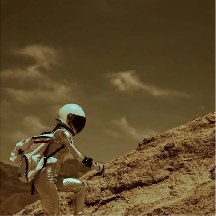 Astronaut climbing a rocky hill